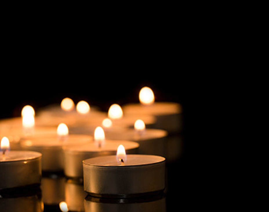 Stock image of lighted tealight candles against a dark background