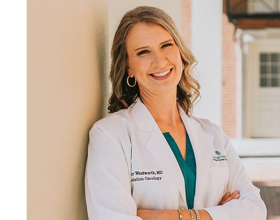 Dr. Stacy Wentworth in a white coat, smiling facing forward in an outdoor setting.