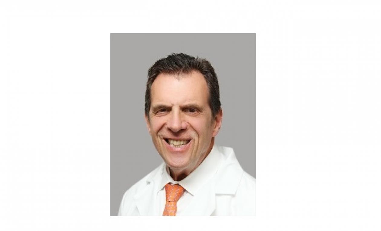 Dr. Marc Citron smiling, facing forward. He is wearing a white coat with a bright orange tie.