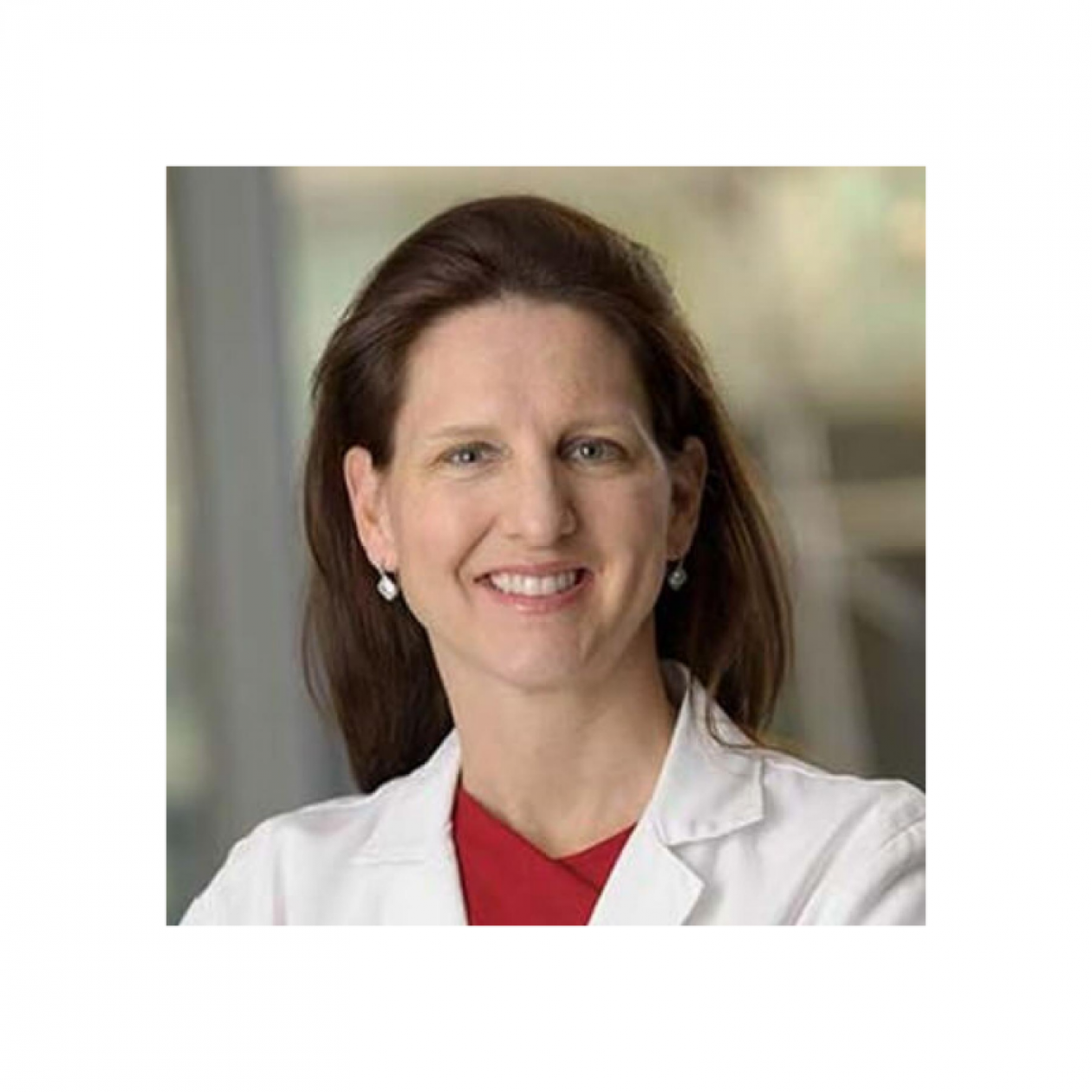 Headshot of Dr. Kathryn Beal, a new Board Member. She is wearing a white coat with red shirt underneath, and has long brown hair, and is facing forward while smiling.