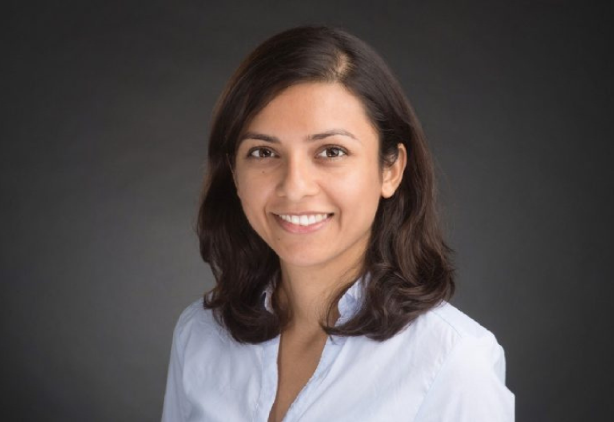 Dr. Sahaja Acharya headshot. She is smiling facing forward against a dark-gray background.