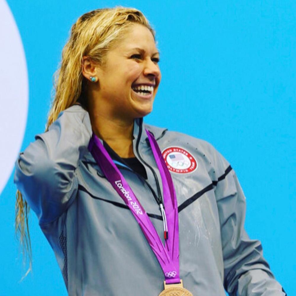 Liz Beisel smiling in a candid shot while on the podium with her medal at the 2012 Olympic Games.