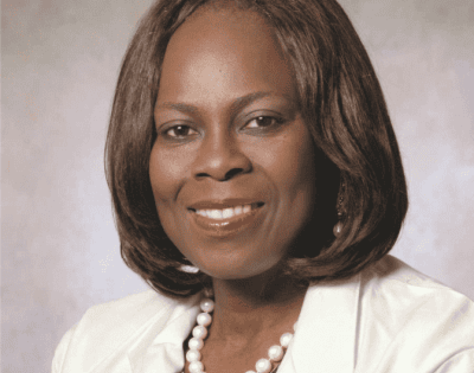 Dr. Olopade headshot. She is smiling, facing forward, wearing a white jacket, with a white pearl necklace.