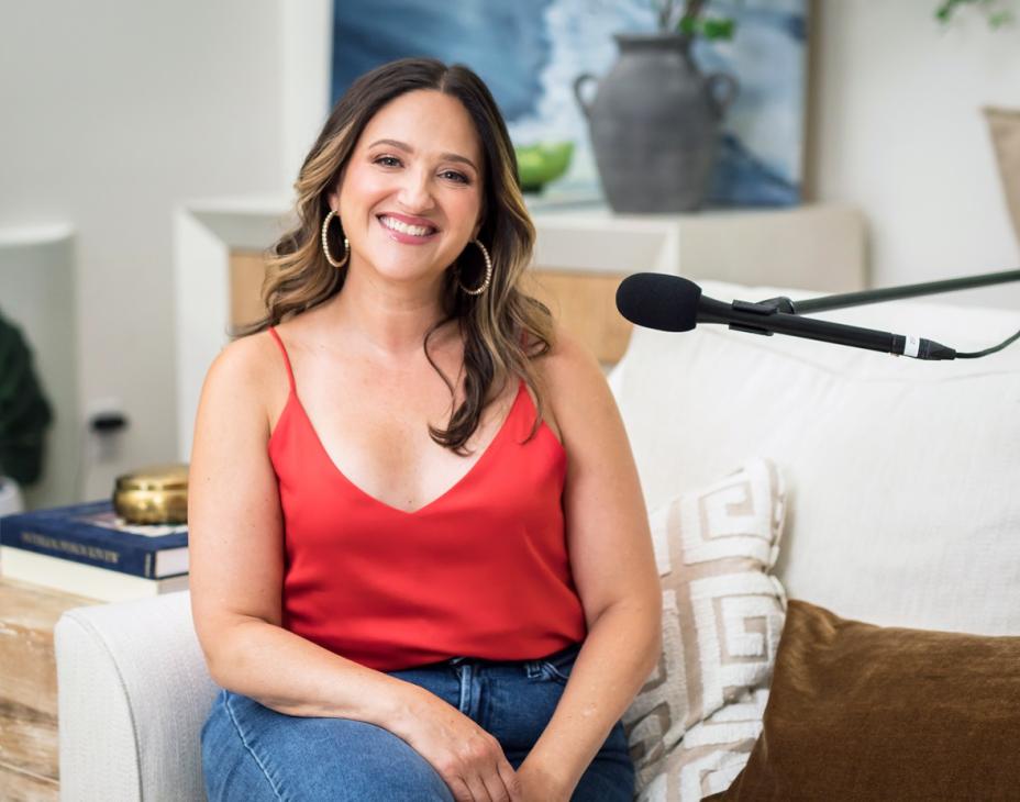 Melissa Berry sitting near a microphone. She's wearing a red shirt and is smiling facing forward.