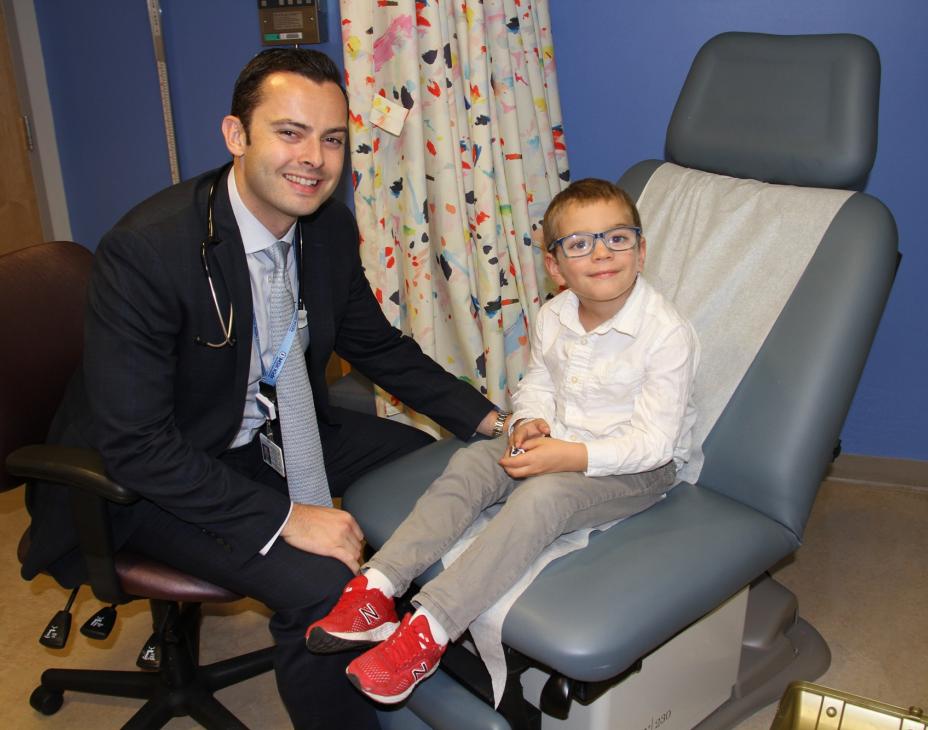 Dr. Michael Kinnaman sitting next to Calum in a clinical setting. Both are smiling facing forward.