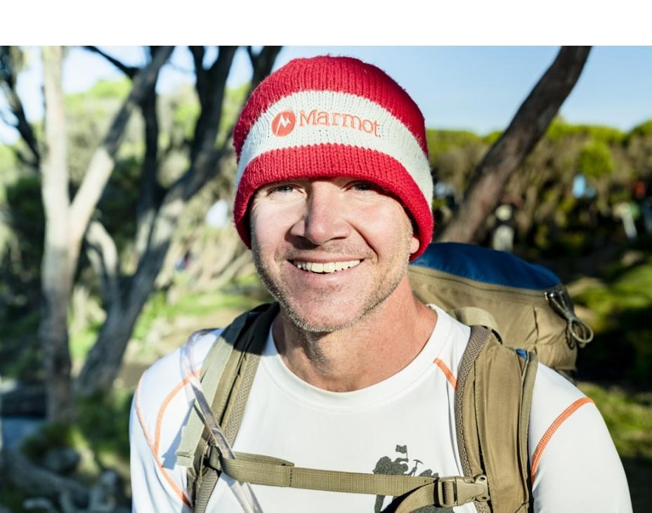 Sean Swarner in an outdoor setting wearing a climber backpack, smiling facing forward