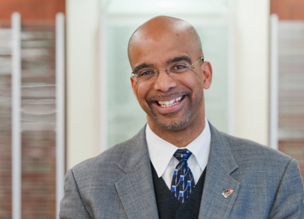 Dr. Clyde Yancy in a gray coat, smiling facing forward.