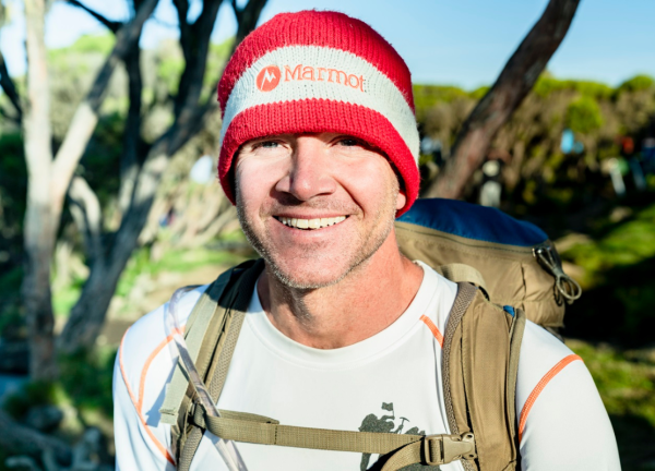 Sean Swarner in an outdoor setting wearing a climber backpack, smiling facing forward