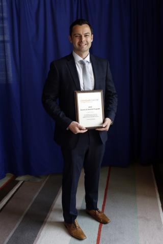 Dr. Michael Kinnaman holding his 2019 Young Investigator Award plaque at the ASCO Annual Meeting