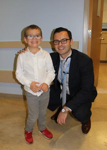 Calum (left) standing next to Dr. Michael Kinnaman (right) in a clinical setting. Both are smiling and facing forward.