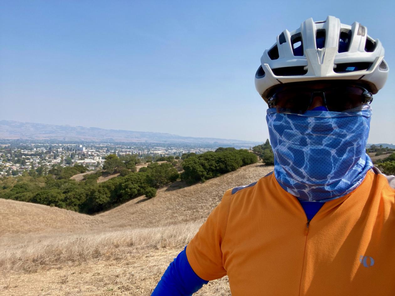 Mark Crafts in an orange shirt, silver helmet, black sunglasses, and electric-blue face-mask