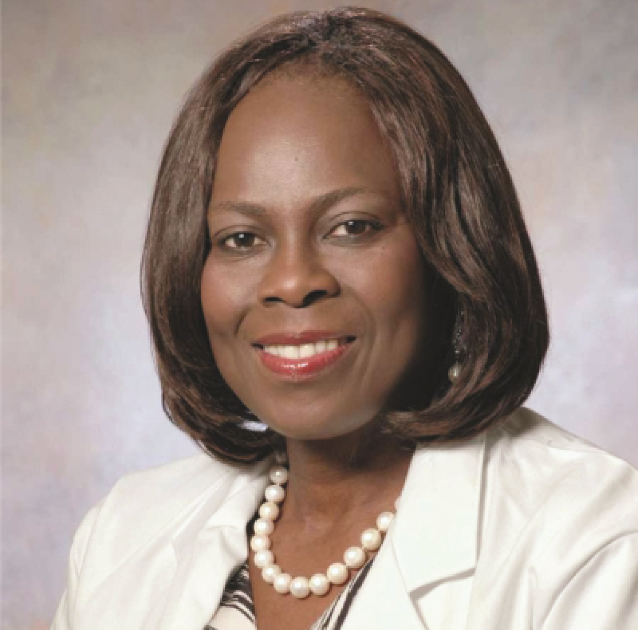 Dr. Olopade headshot. She is smiling, facing forward, wearing a white jacket, with a white pearl necklace.