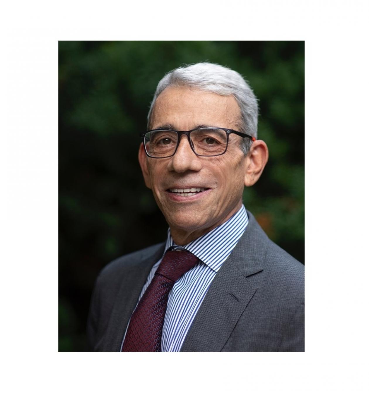 Dr. Eric P. Winer headshot. He is smiling facing forward. He has white hair, is wearing glasses, and is in a gray suit.