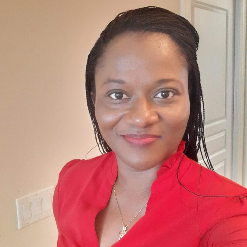 Dr. Aba Scott wearing a red shirt and smiling facing forward. She has shoulder-length black hair.