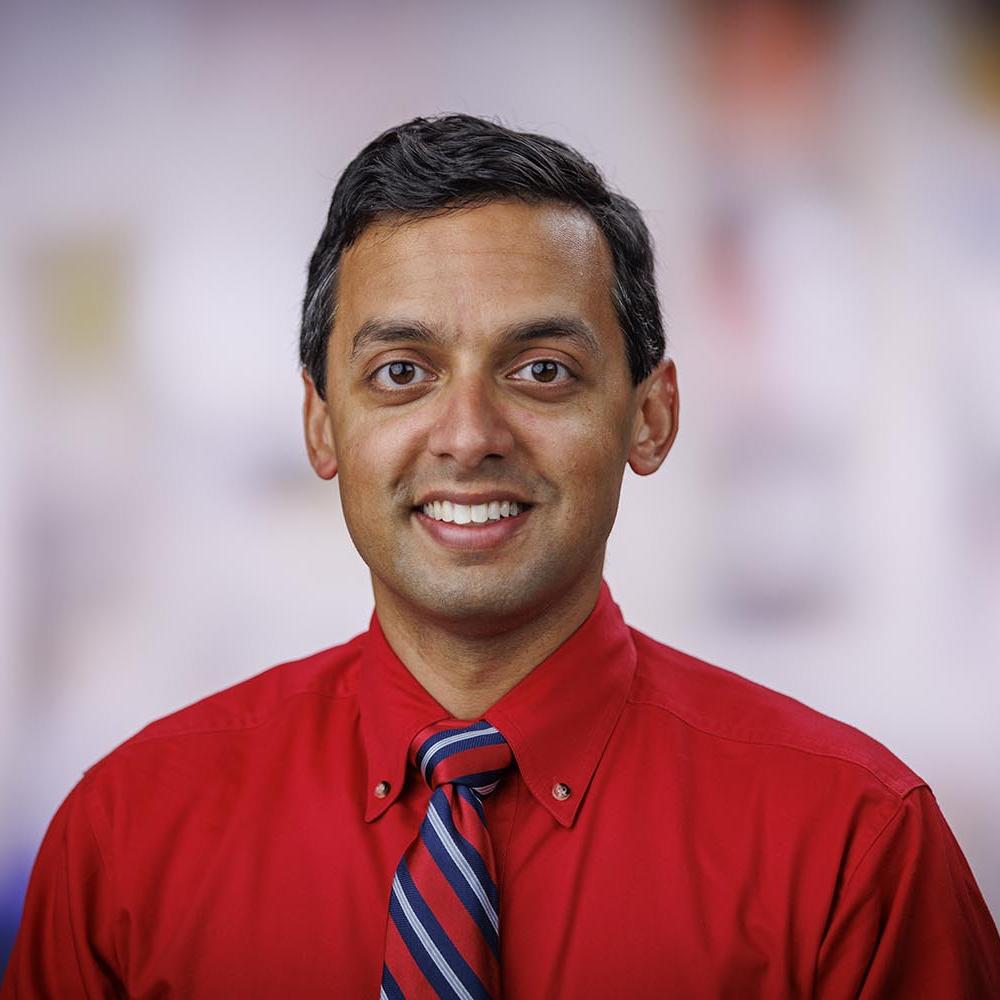 Headshot of Dr. Rahul Banerjee in a clinical setting. He is smiling facing forward