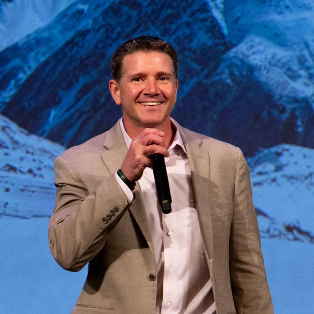 Sean Swarner holding a microphone and speaking at a public event