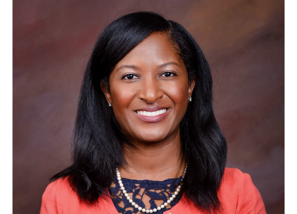 Dr. Erica Stringer-Reasor smiling facing forward against a brown background. She has shoulder-length black hair.